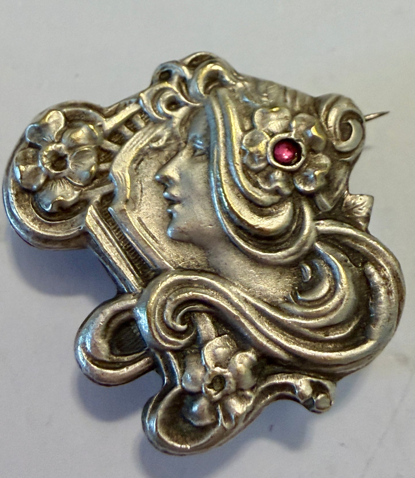 Spilla Liberty volto di donna con fiori e volute, pasta vitrea rosa, primo ‘900