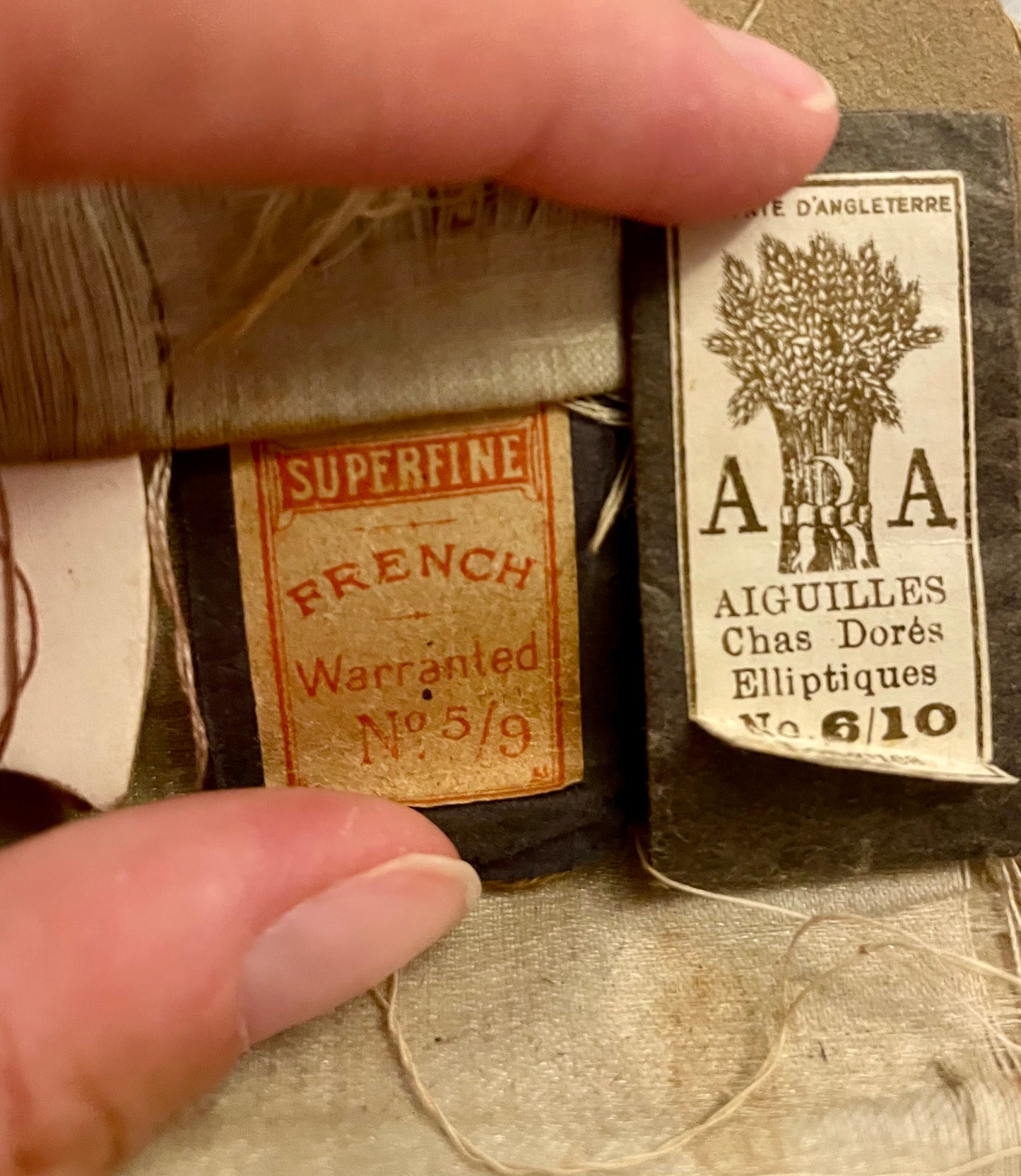 Antico set da cucito vittoriano in bustina, completo di aghi d’epoca, strumenti in ferro, osso e specchietto ovale.