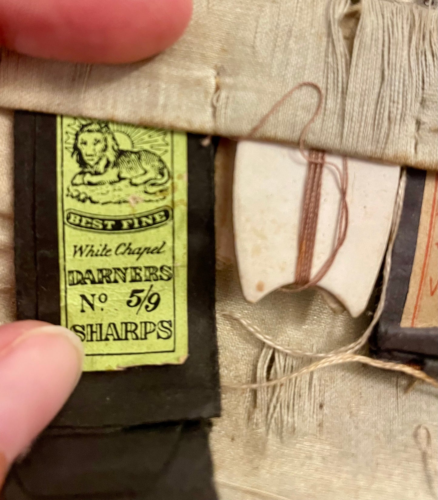 Antico set da cucito vittoriano in bustina, completo di aghi d’epoca, strumenti in ferro, osso e specchietto ovale.