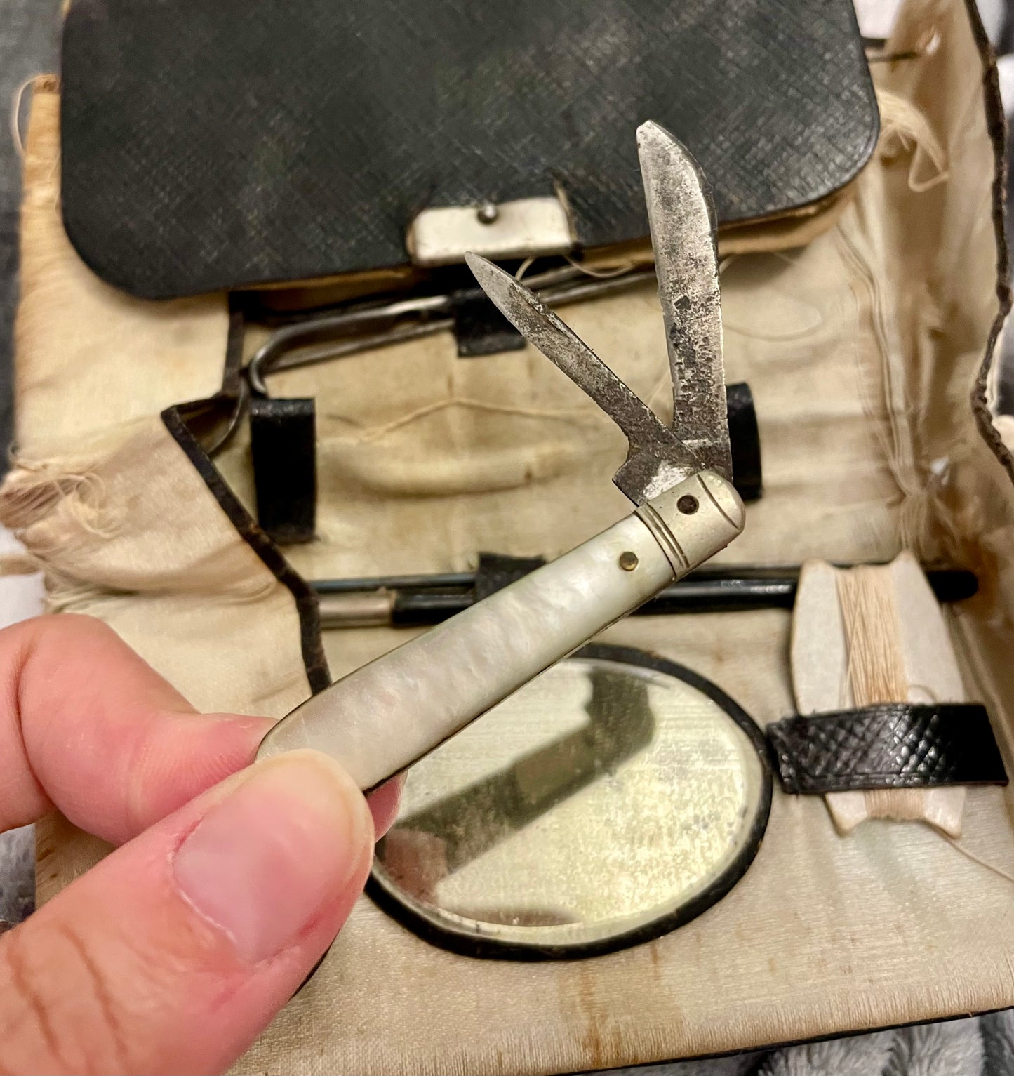 Antico set da cucito vittoriano in bustina, completo di aghi d’epoca, strumenti in ferro, osso e specchietto ovale.