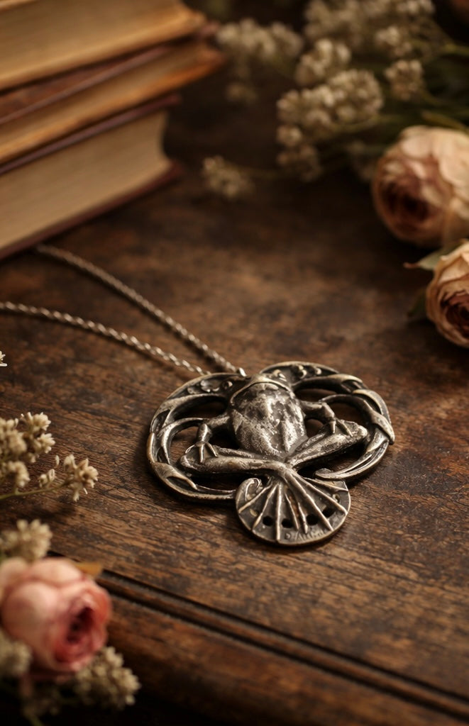 Medaglione liberty placcato argento, firmato, a guisa di rana in cornice floreale