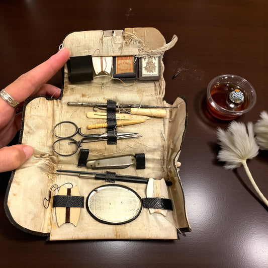 Antico set da cucito vittoriano in bustina, completo di aghi d’epoca, strumenti in ferro, osso e specchietto ovale.