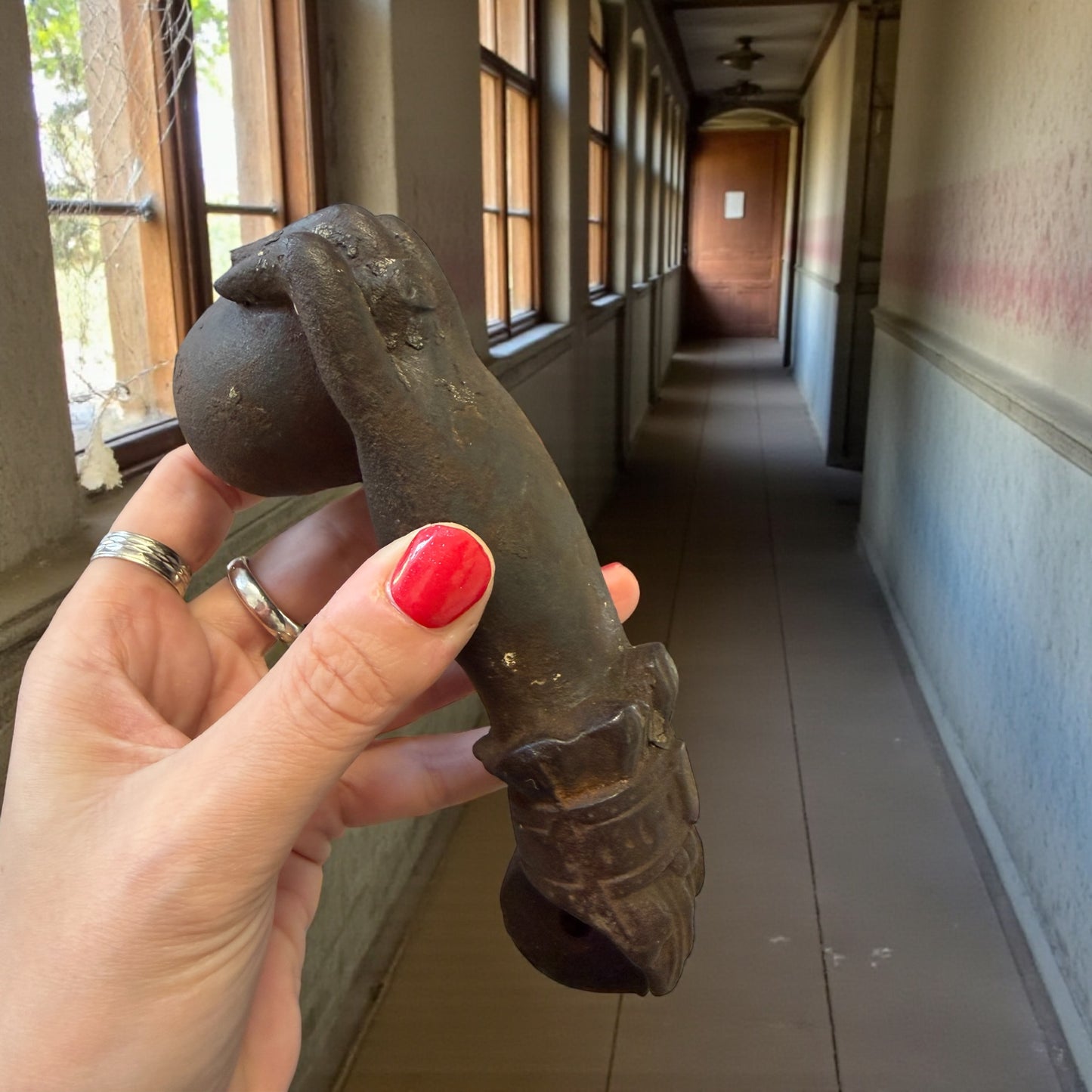 Battente antico in ghisa, mano femminile che bussa