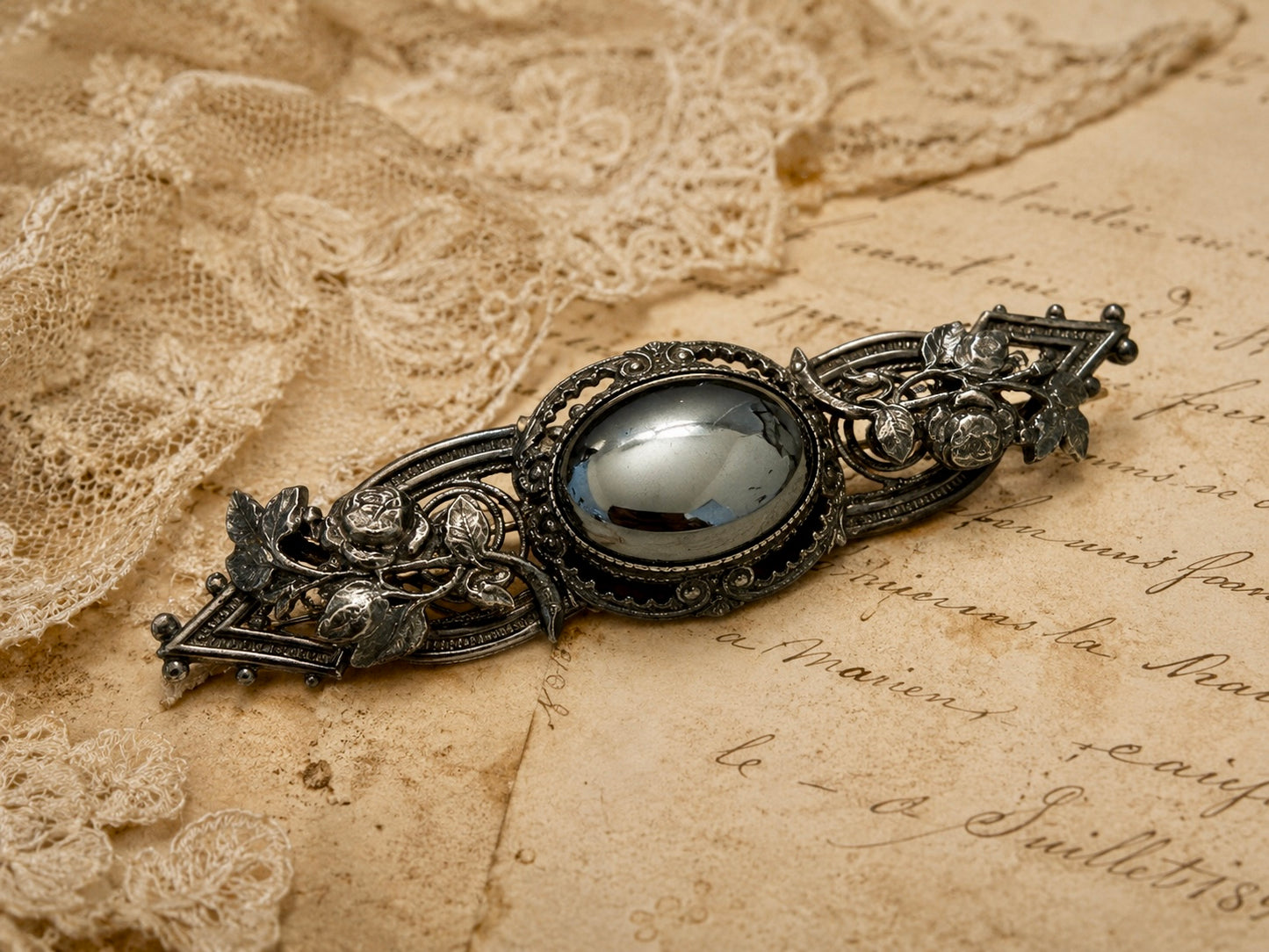 Spilla placcata argento con volute di rose e cabochon in ematite, anni ‘40