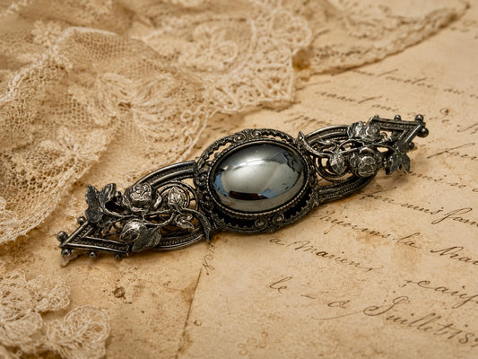 Spilla placcata argento con volute di rose e cabochon in ematite, anni ‘40