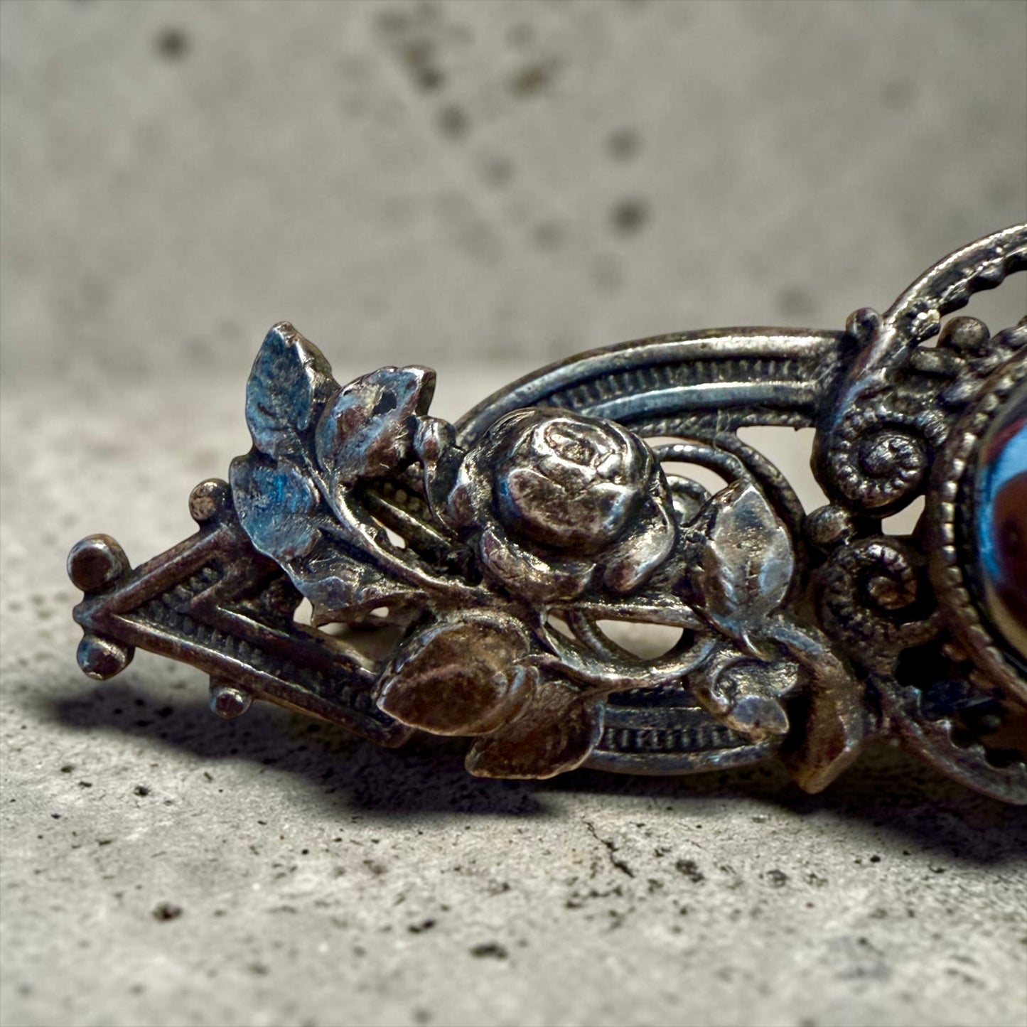 Spilla placcata argento con volute di rose e cabochon in ematite, anni ‘40