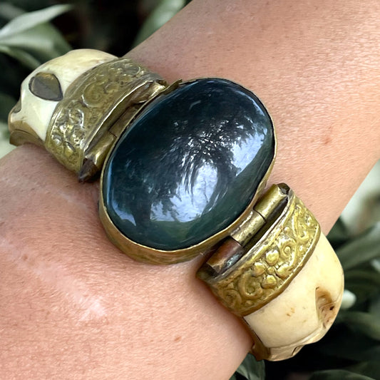 Bracciale rigido in osso con chiusura a baionetta, decorazioni in ottone e cabochon centrale pietra dura